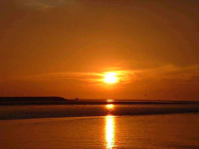 Foto ondergaande zon op de Waddenzee